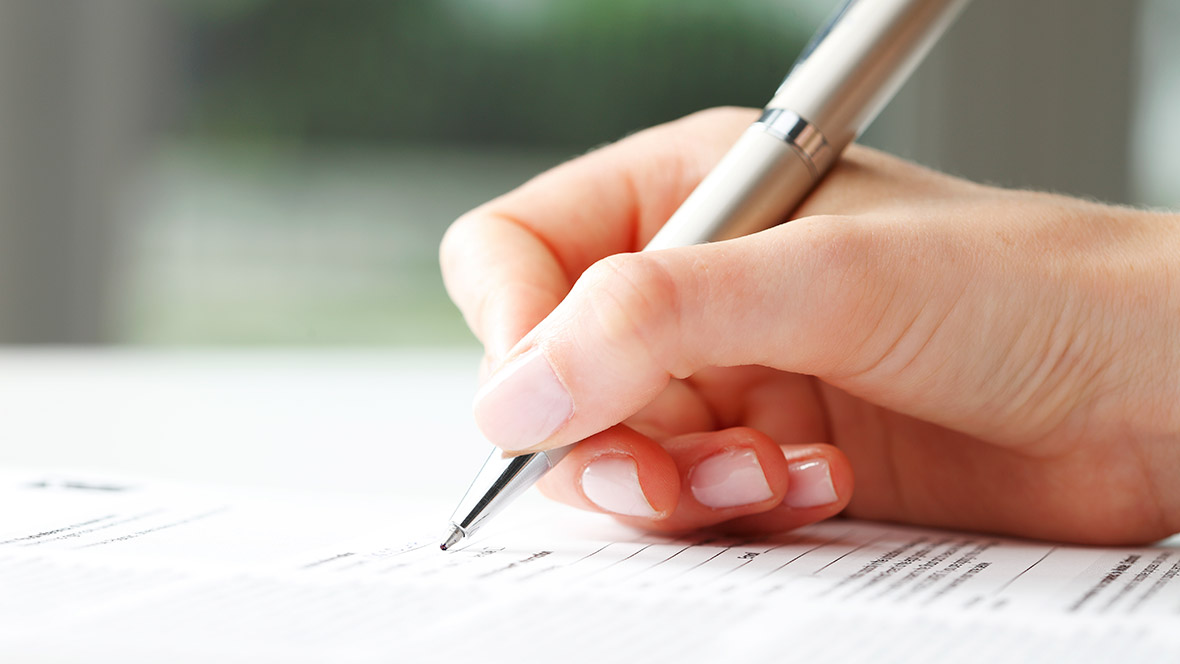 Eine Frau füllt handschriftlich ein Formular aus. Nahaufnahme der Hand. Eine Frau füllt handschriftlich ein Formular aus. Nahaufnahme der Hand.