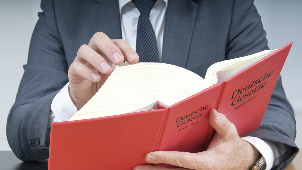 Ein Mann blättert in einem Gesetzbuch mit dem Titel „Deutsche Gesetze"