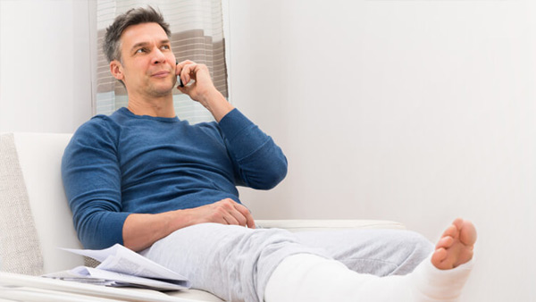 Ein Mann mit Gipsbein telefoniert Ein Mann mit Gipsbein telefoniert