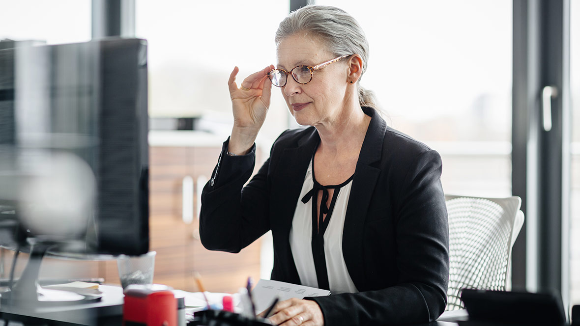 Eine Frau am Büroarbeitsplatz blickt auf einen Monitor. Eine Frau am Büroarbeitsplatz blickt auf einen Monitor.