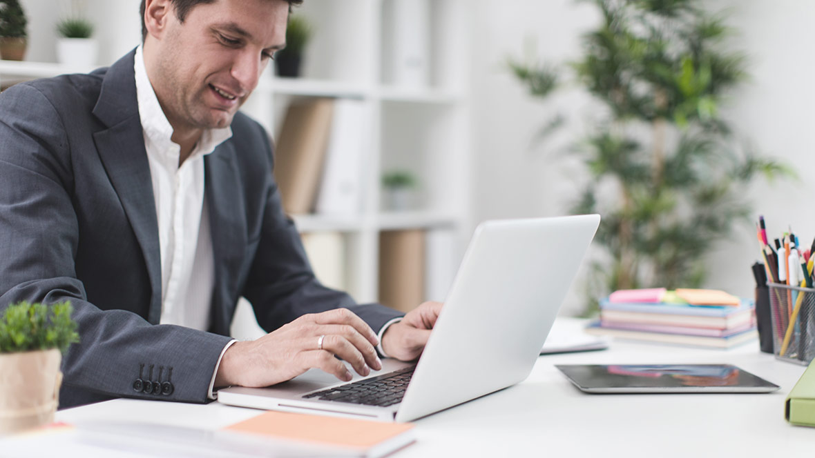 Ein Mann ermittelt in einem Büro an einem Laptop den Zuschuss zum Muterschaftsgeld. Ein Mann ermittelt in einem Büro an einem Laptop den Zuschuss zum Muterschaftsgeld.