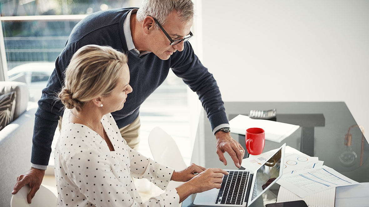 Eine Frau und ein Mann vor einem Laptop am Schreibtisch Eine Frau und ein Mann vor einem Laptop am Schreibtisch