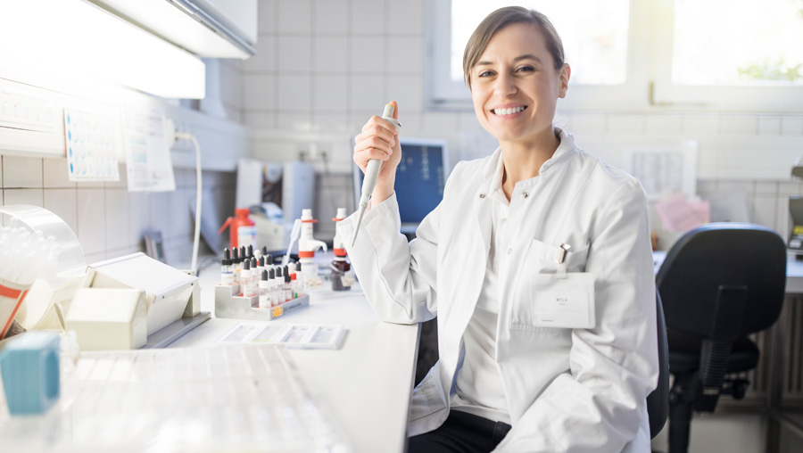 Eine Labormitarbeiterin sitzt mit einer Pipette in der Hand im Labor. Eine Labormitarbeiterin sitzt mit einer Pipette in der Hand im Labor.
