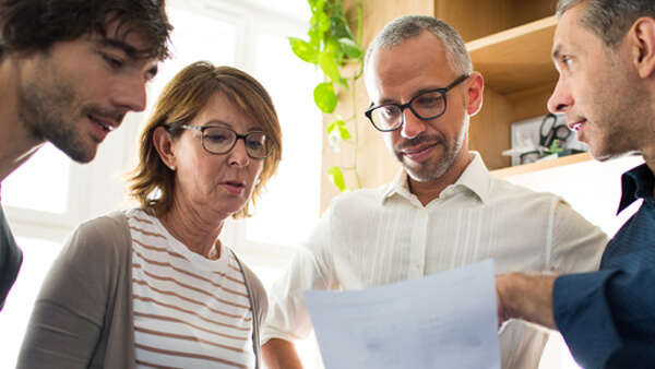 Vier Arbeitskollegen schauen gemeinsam auf ein Dokument. Vier Arbeitskollegen schauen gemeinsam auf ein Dokument.