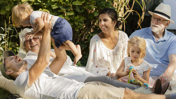 Eine Familie sitzt im Garten. Der Vater hebt ein Kind in die Luft. Eine Familie sitzt im Garten. Der Vater hebt ein Kind in die Luft.